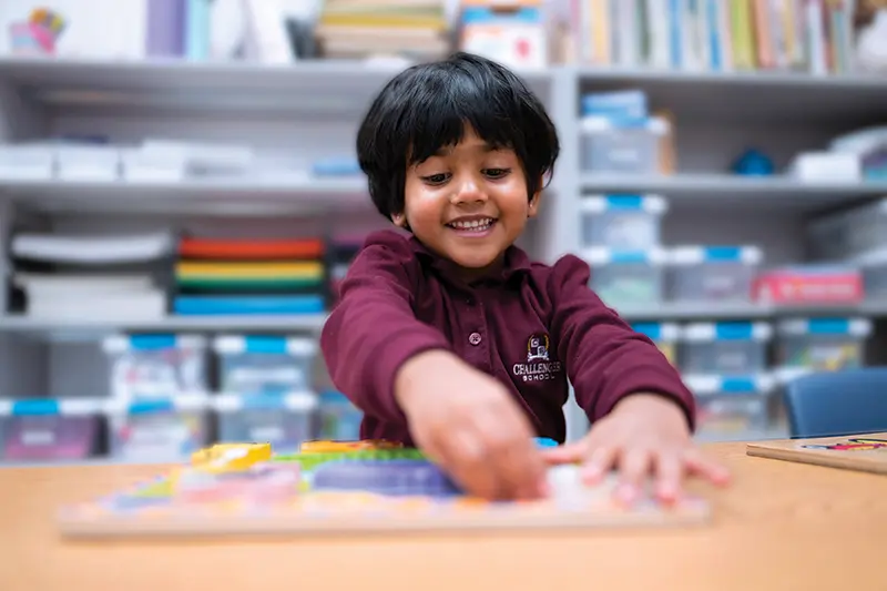 A child smiling, playing with toys at a desk