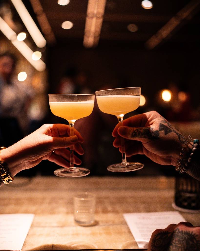 Image shows people clinking cocktails together at Bandista in Houston. 