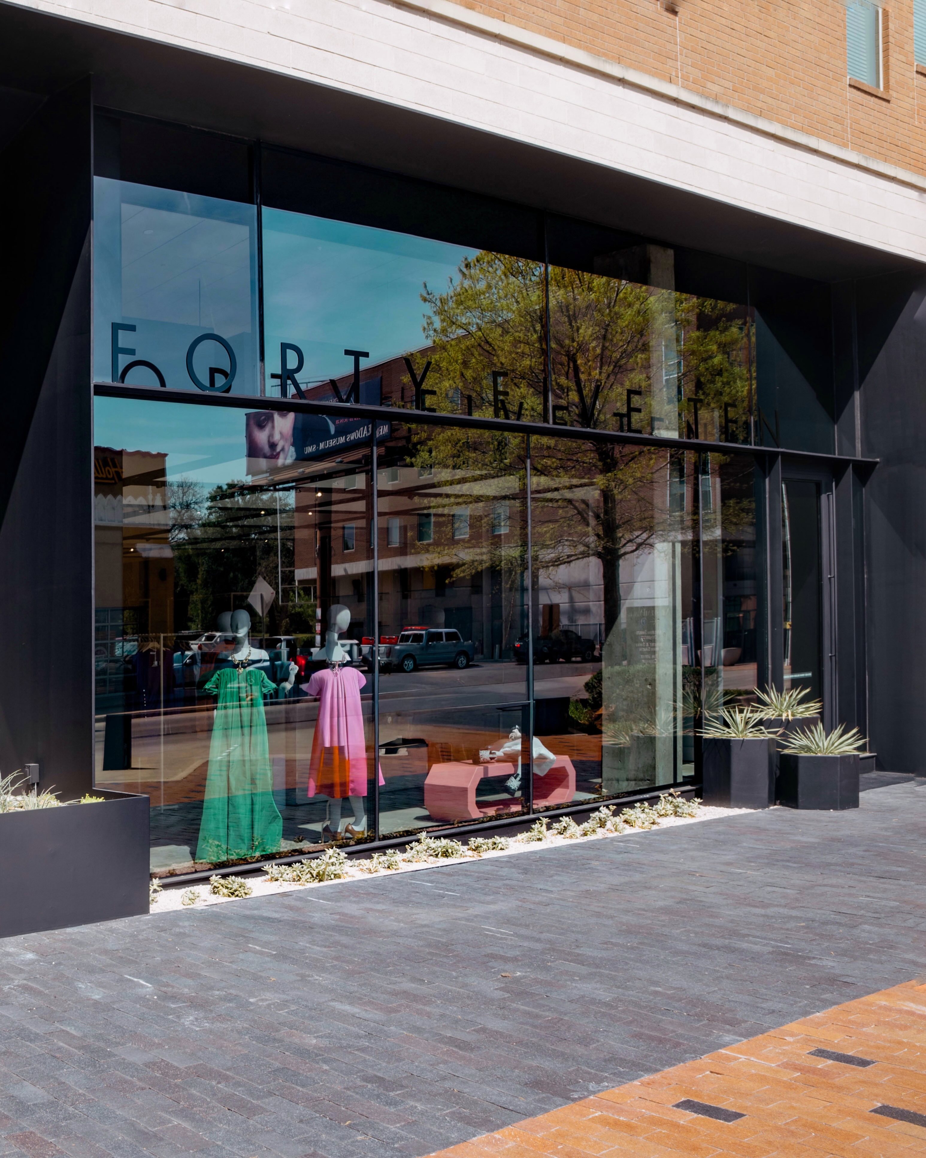 Glass storefront of Forty Fifteen building reflecting nearby trees and buildings.