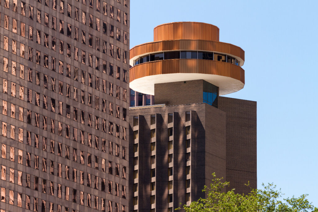 Image shows Spindletop restaurant in Houston with another building in the foreground.