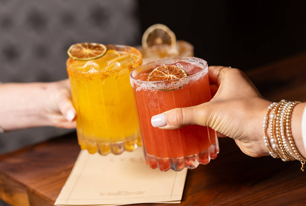 Image shows people holding up margaritas. 