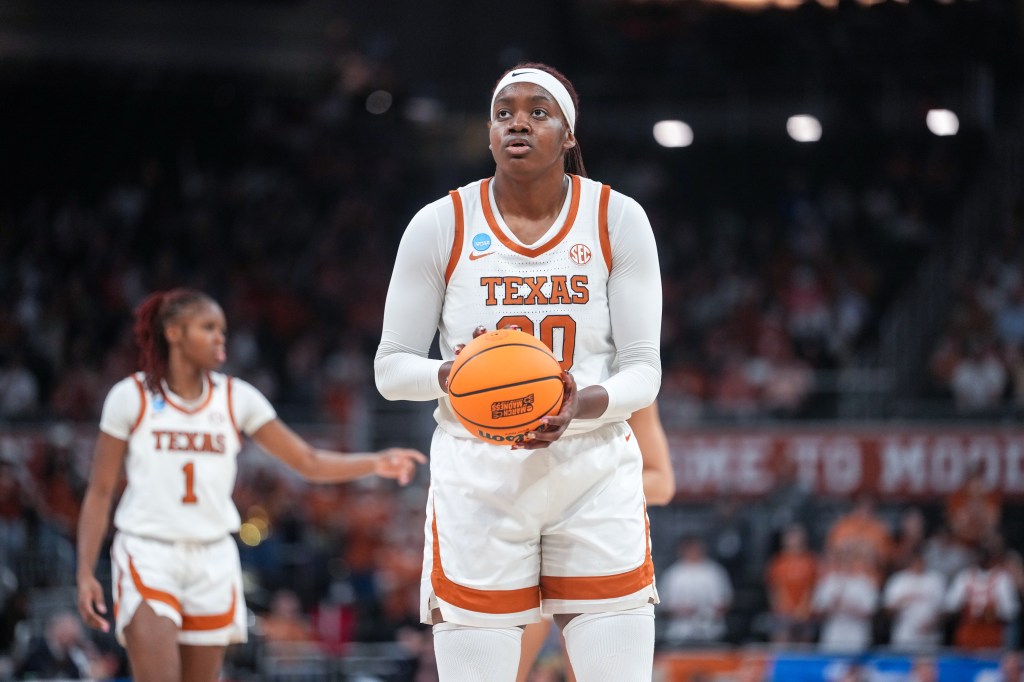 A female basketball player in a white uniform with "TEXAS" and "30" in orange, holding a basketball, looks determinedly during the 2026 NCAA Women's Basketball Tournament.