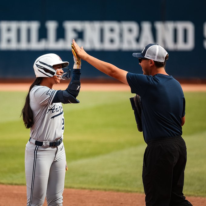 Arizona designated player Tele Jennings celebrates reaching first base with assistant coach Christian Conrad on Apr. 25, 2026