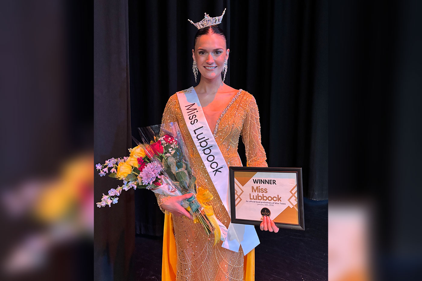 A crowned pageant winner wearing a “Miss Lubbock” sash and gold gown poses on stage, holding a bouquet of flowers and a framed winner’s plaque.