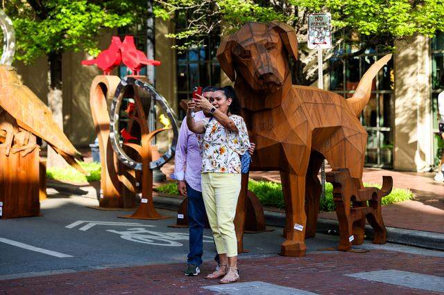 Main Street Arts Festival goers take photos in front of a sculpture at the 2025 Main Street Arts Festival in downtown Fort Worth.