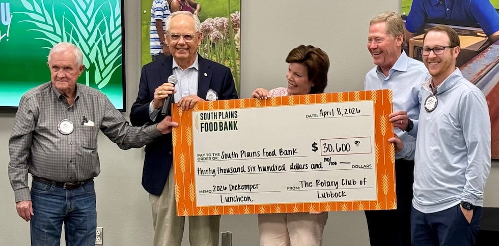 Brent Magers, president of the Rotary Club of Lubbock (holding microphone), presents check to...