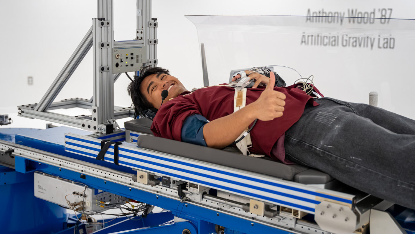 A photo of a student laying on a platform for a centrifuge.