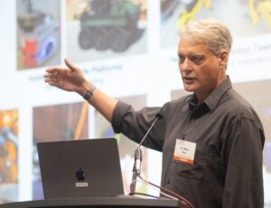 Man at podium points to PowerPoint slides