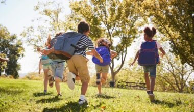 Five school kids running in a field, back view, close up
