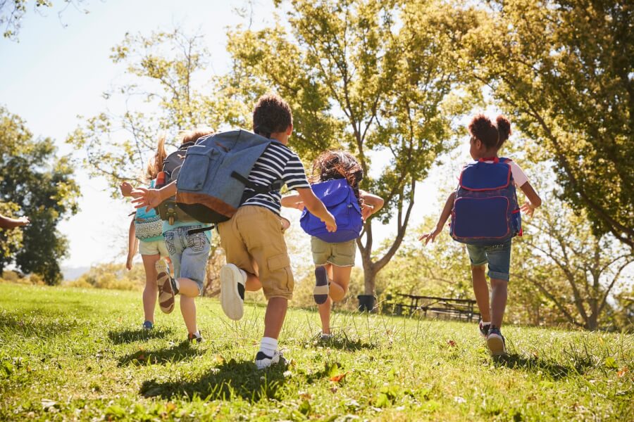Five school kids running in a field, back view, close up