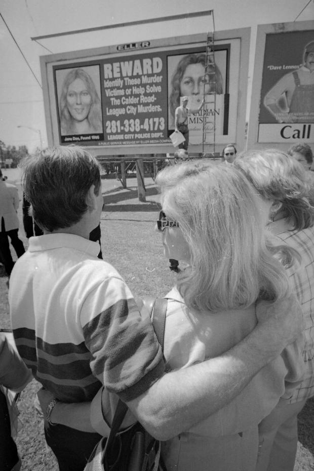 Tim Miller, father of murder victim Laura Miller, hugs his wife, Georgeann, as they look at one of 50 billboards dedicated to unidentified murder victims along Highway 3 in League City, Texas, on May 11, 1998. (Buster Dean/Houston Chronicle via AP)