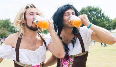 Two men wearing traditional German outfits drinking beer.