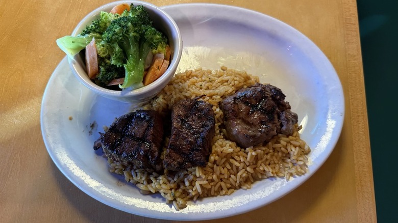 Plate of filet medallions with rice and baked potato from Texas Roadhouse