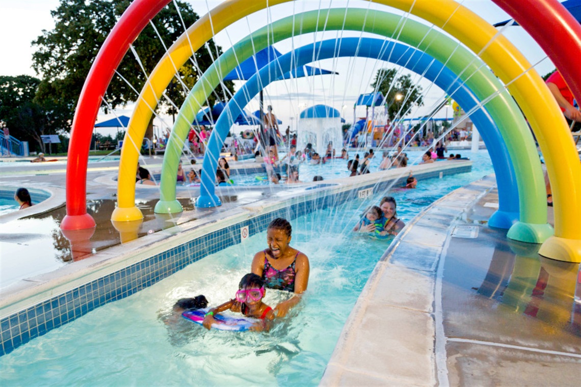 Mom with children passing through Randol Mill's pool rainbow arch.