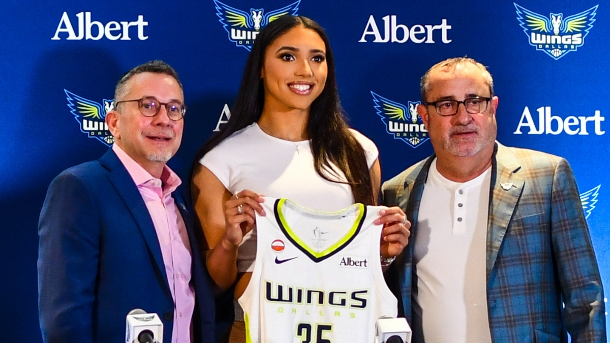 Azzi Fudd holds up her new #35 Dallas Wings jersey alongside General Manager Curt Miller and head coach Jose Fernandez during her introductory press conference in Arlington.