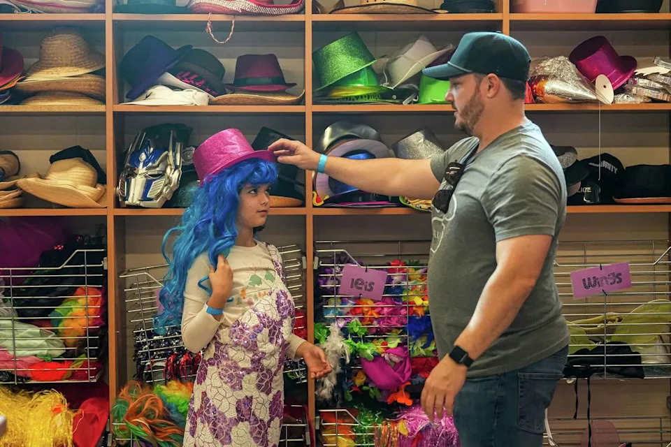 Dustin Mattiza puts a hat on his daughter, Ava, in a dressing room at Camp For All. The camp offers camps for families who have children with developmental differences or have a chronic illness. (Aaron E. Martinez/Austin American-Statesman)