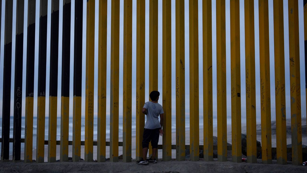 A boy looks through a border wall separating Mexico from the United States, Nov. 26, 2024, in Tijuana, Mexico. (AP Photo/Gregory Bull)