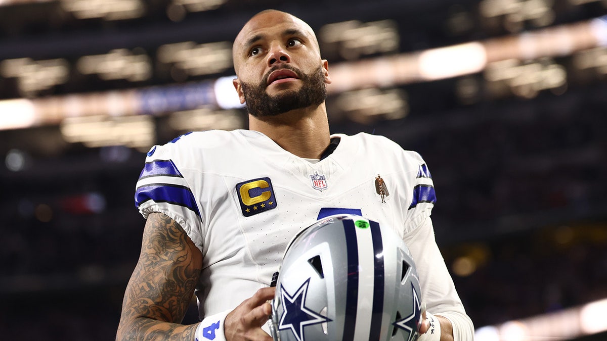 Dallas Cowboys quarterback Dak Prescott standing on the field at AT&T Stadium.