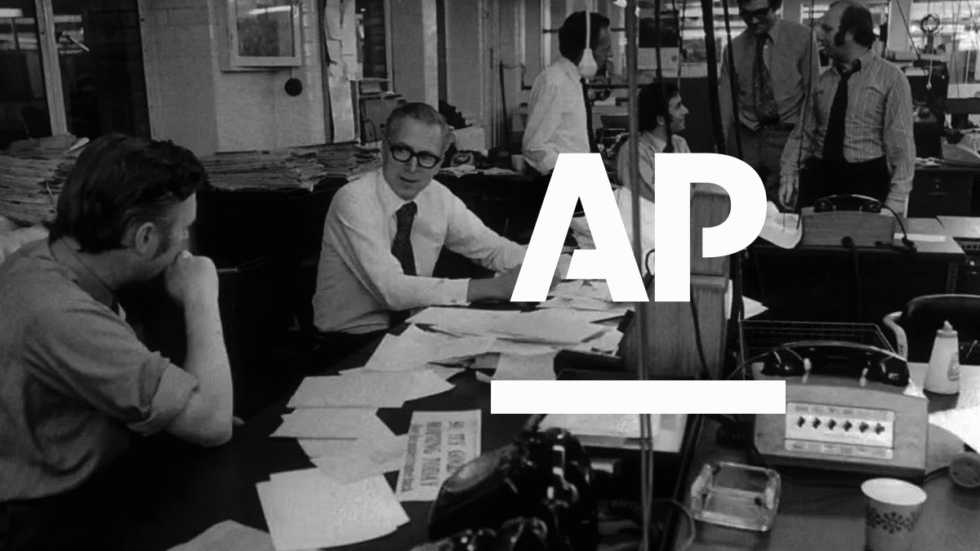 A historical picture of a newsroom from the 1970's with the AP logo in white super imposed.