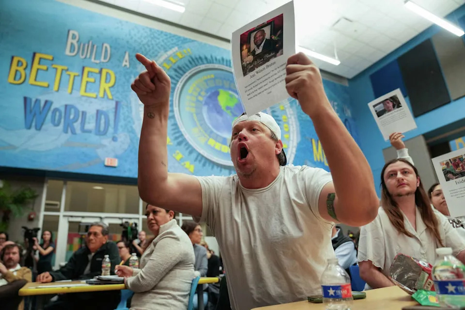 Robert Saulter holds a photo of a man who died in ICE custody as he questions Police Chief Lisa Davis during a town hall to address community concerns about Austin police officers cooperating with federal immigration agents at Govalle Elementary School in Austin Thursday, Feb. 5, 2026. (Mikala Compton/Austin American-Statesman)