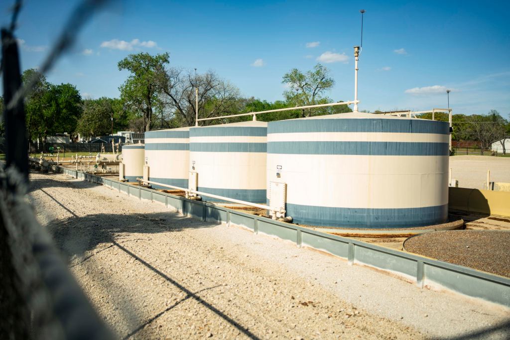 Giant containers sit in a row on a fenced off site.