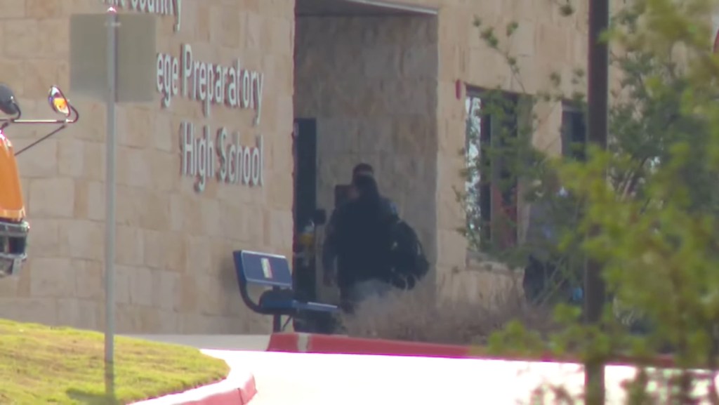 A police officer standing outside Hill Country College Preparatory High School.