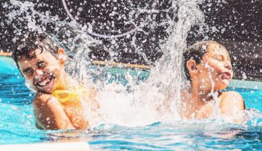 Two boys at the swimming pool splashing water and having fun. Friends playing on the water of a summer day.