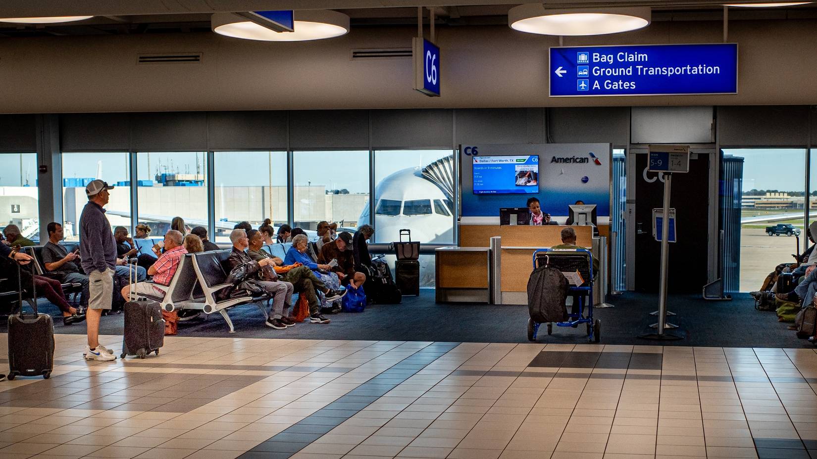 Passengers wait to board an American Airlines flight at a U.S. airport gate