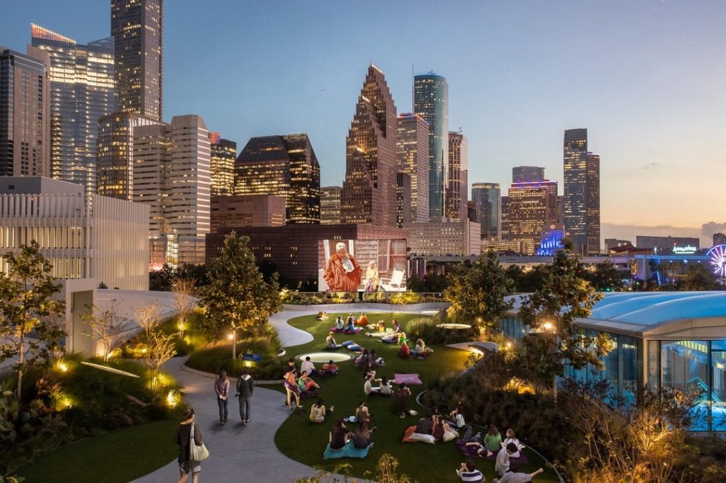 Image shows a group of people watching outdoor movies at POST market with a skyline backdrop.