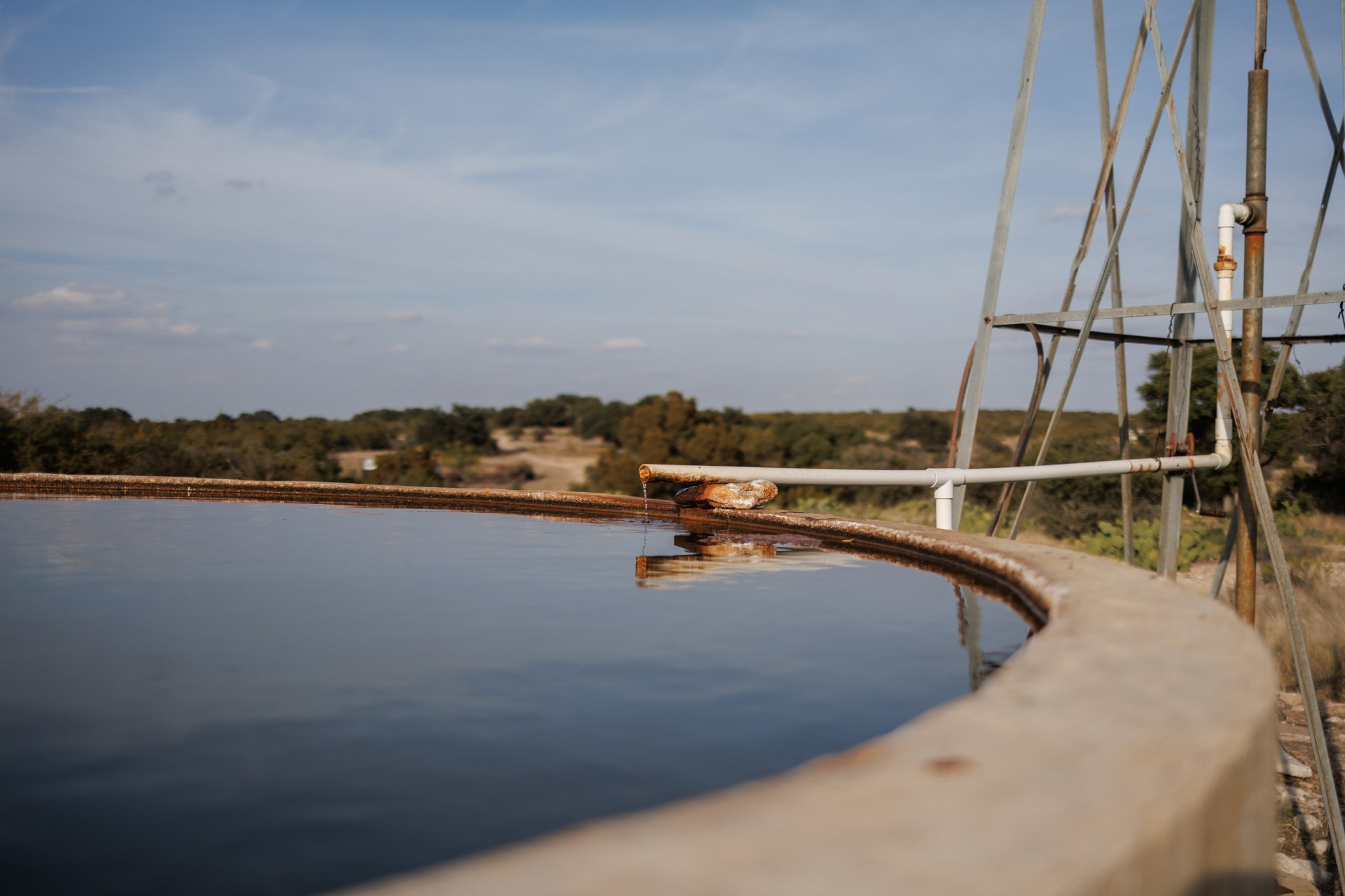 A a pipe drips water into a clean well on Jackie Lynn Chestnutt’s property in Knickerbocker, Texas on Tuesday, November 18, 2025. A large number of orphan oil wells are dotted around her large property, causing worry that ground water could be contaminated by leeching oil, produced water or chemicals.