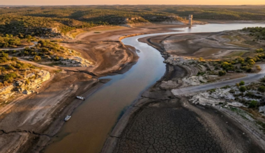 Aerial view shows a drought-affected riverbed with low water levels and cracked soil (Photo generated by Gemini)