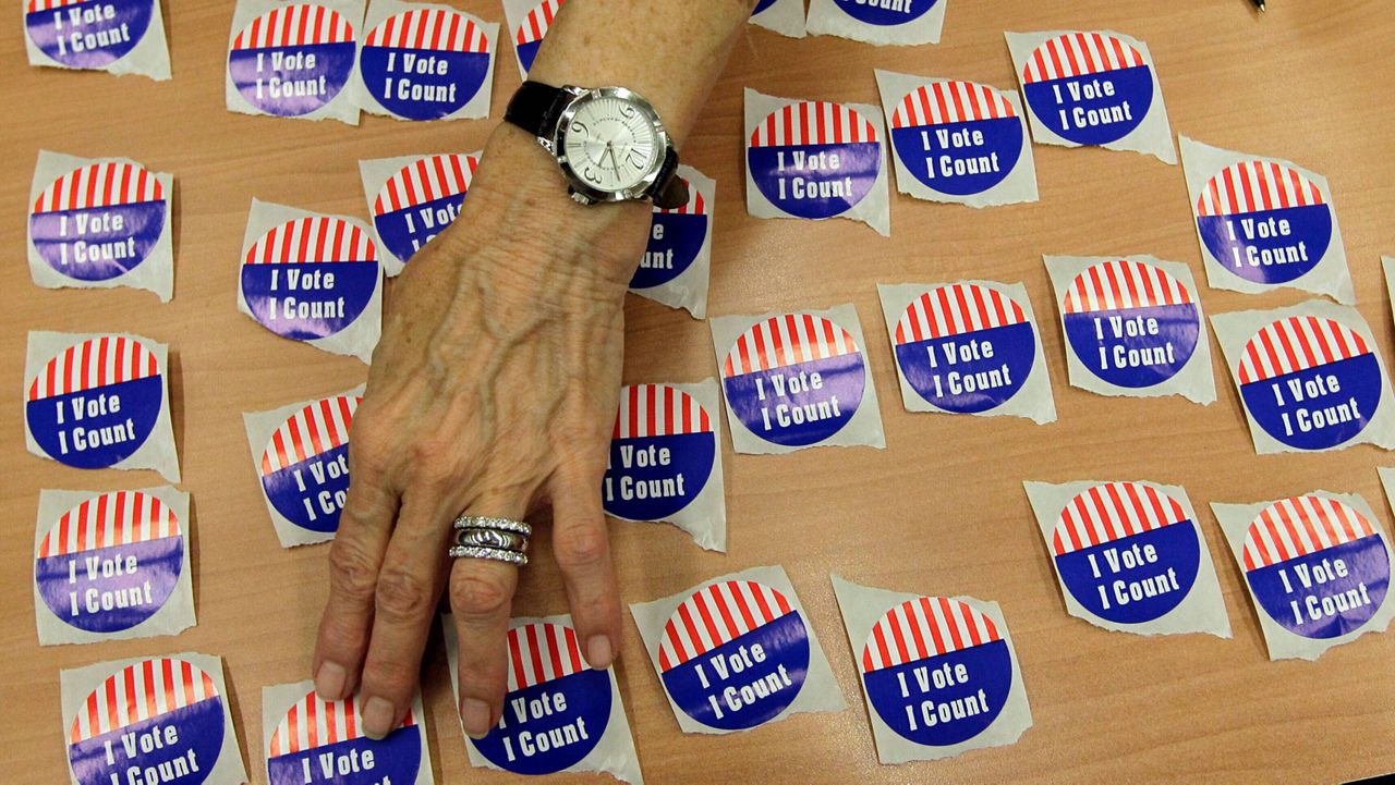 An election judge arranges "I Vote, I Count" stickers on a table in the Marion County Clerks office as voters cast early ballots in Indianapolis, Oct. 22, 2012. (AP Photo/Michael Conroy)