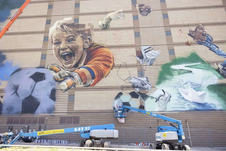 Muralists work on a soccer themed mural ahead of the 2026 FIFA World Cup on the former Jesse R. Dawson State Jail building at 106 W. Commerce Street in Dallas, Thursday, May 14, 2026. The mural will be created by internationally acclaimed artist ROOSART, curated and produced by Street Art for Mankind, and local Dallas artist Daniel Yanez. (Juan Figueroa/The Dallas Morning News)