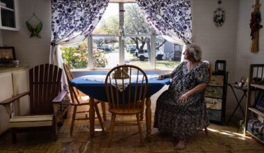 Diane Shields, 77, sits at her kitchen table and looks out the window in Fort Worth on March 20, 2026. Shields said she bought her trailer home 24 years ago because she “fell in love with the windows in the kitchen.” Floor tiles are now peeling away in the kitchen. Years ago, she tried to replace the tiles while making minor repairs to her home. However, they would not come up she said.