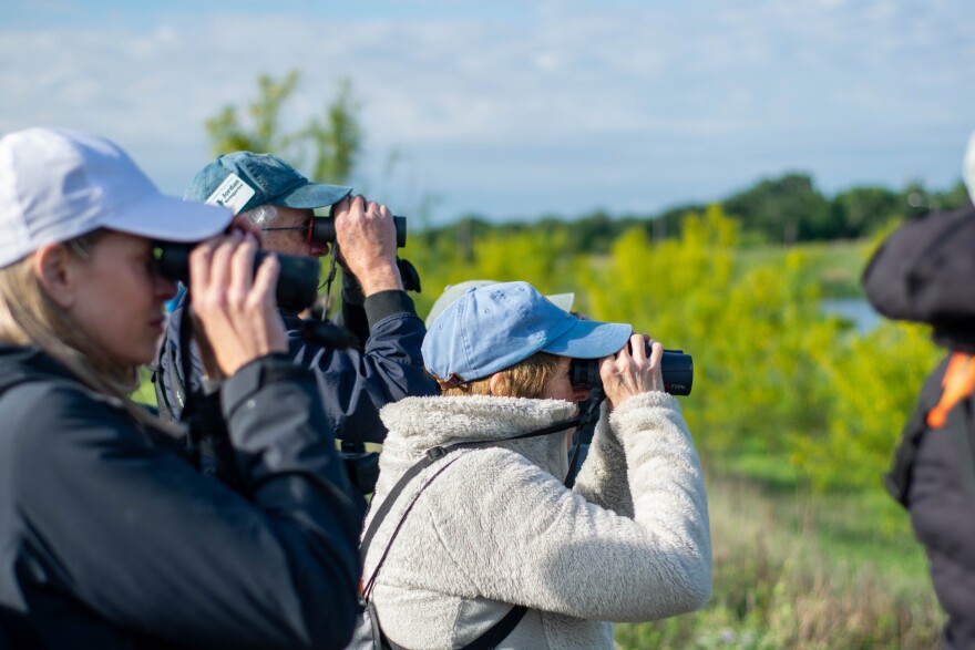 A group of people look into binoculars outdoors.