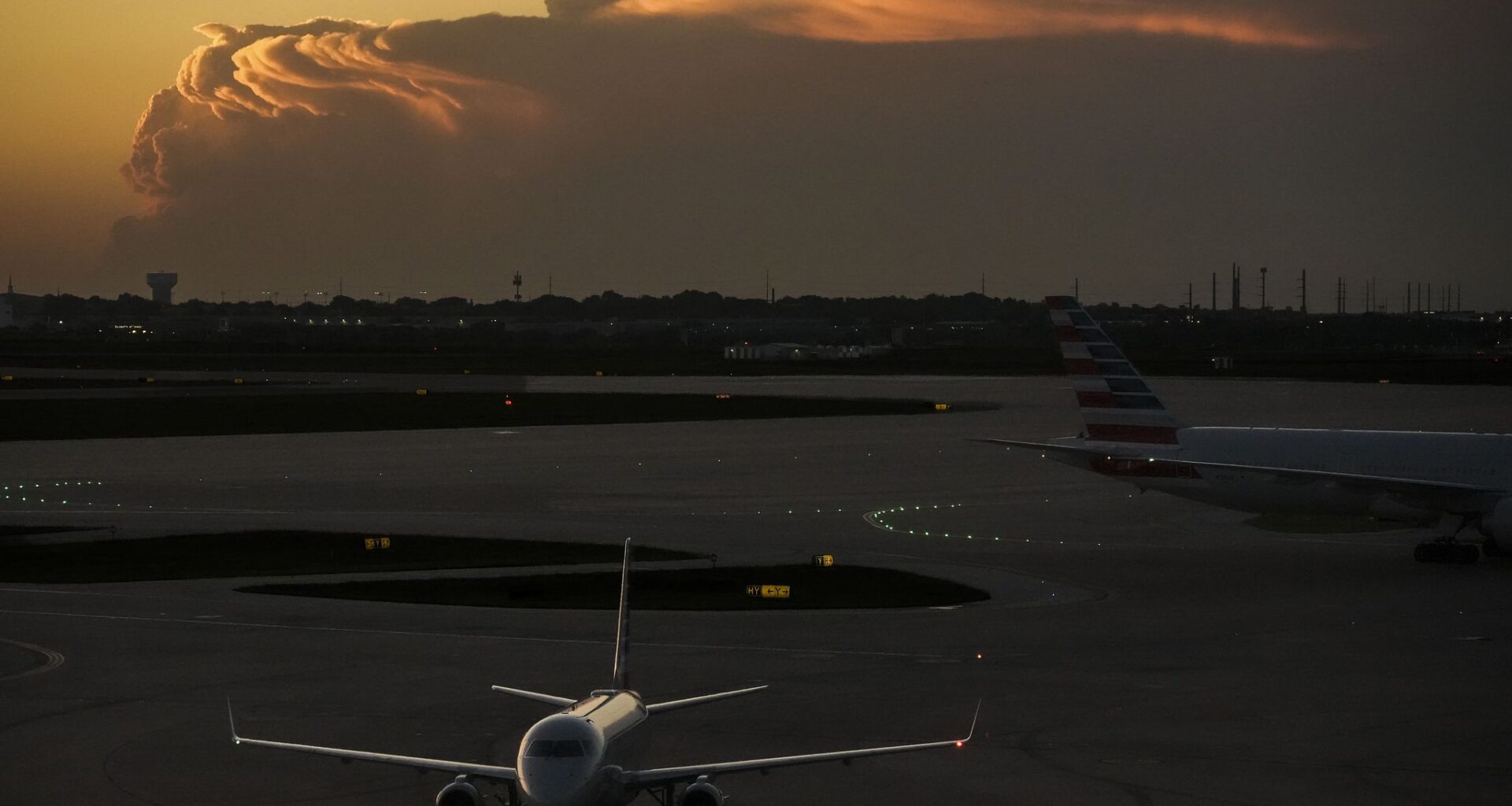 American Airlines planes taxi toward Terminal B at DFW Airport as storm clouds are seen on the horizon on Friday, April 24, 2026.