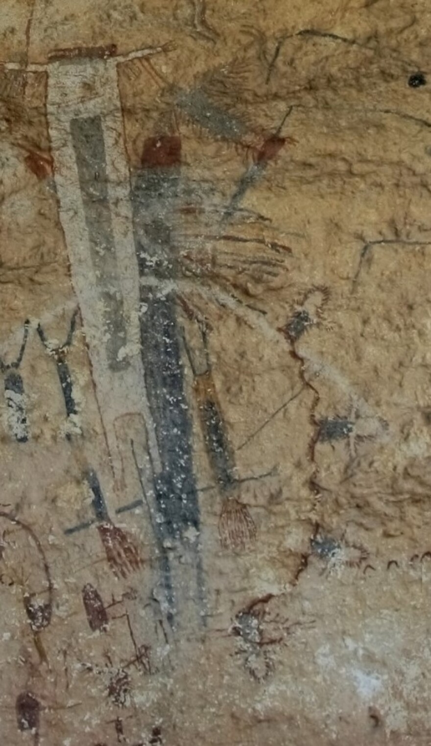A pictograph on the White Shaman Mural. It’s a curved line. Coming off of the line at regular intervals are four matching, symbols that look like knives with gray handles and white blades.