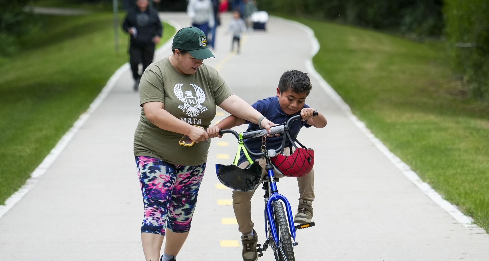 Principal Princess Martinez helps Dylan Leyva, 7, try out his new bicycle as students, staff and families from Eduardo Mata Montessori School ride and walk on the nearby Santa Fe Tail for National Bike & Roll to School Day in Dallas, Wednesday, May 6, 2026. Leyva was the winner of a drawing awarding a new bike to a lucky student.