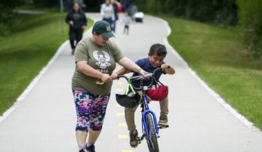 Principal Princess Martinez helps Dylan Leyva, 7, try out his new bicycle as students, staff and families from Eduardo Mata Montessori School ride and walk on the nearby Santa Fe Tail for National Bike & Roll to School Day in Dallas, Wednesday, May 6, 2026. Leyva was the winner of a drawing awarding a new bike to a lucky student.