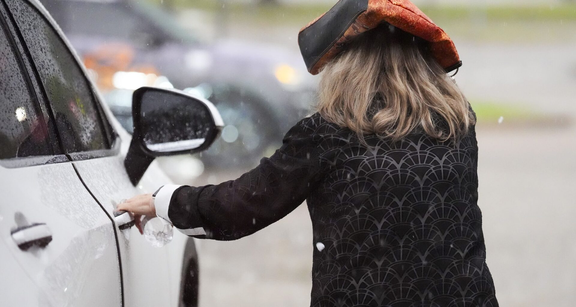 A woman runs to a car as heavy rain and hail fall in Rowlett, Monday, April 27, 2026.