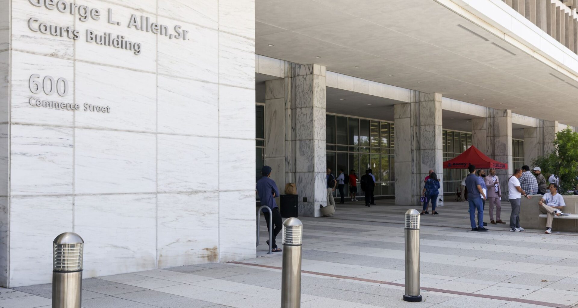 People stand outside the George Allen Courts Building after a water leak, Tuesday, July 2, 2024, in Dallas.