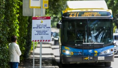 A sign warns of the possible closure of the bus stop as a woman waits for a DART route 237 bus on Preston Road at Livingston in Highland Park, Monday, May 4, 2026.