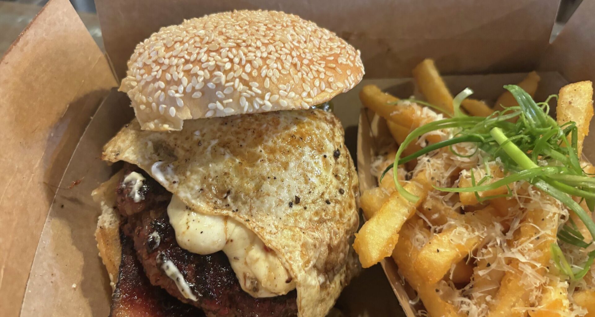 A spicy brisket burger with eggs and two thick strips of brisket, and a side of truffle fries at Black Board Bar B Q in Sisterdale, Texas.  