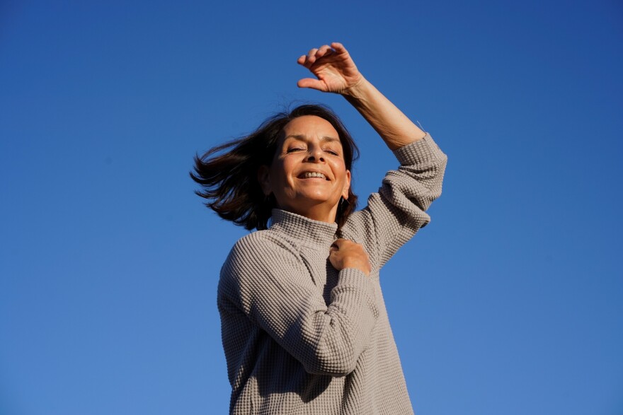 Kathy Dunn Hamrick smiling with an arm raised against the blue sky.