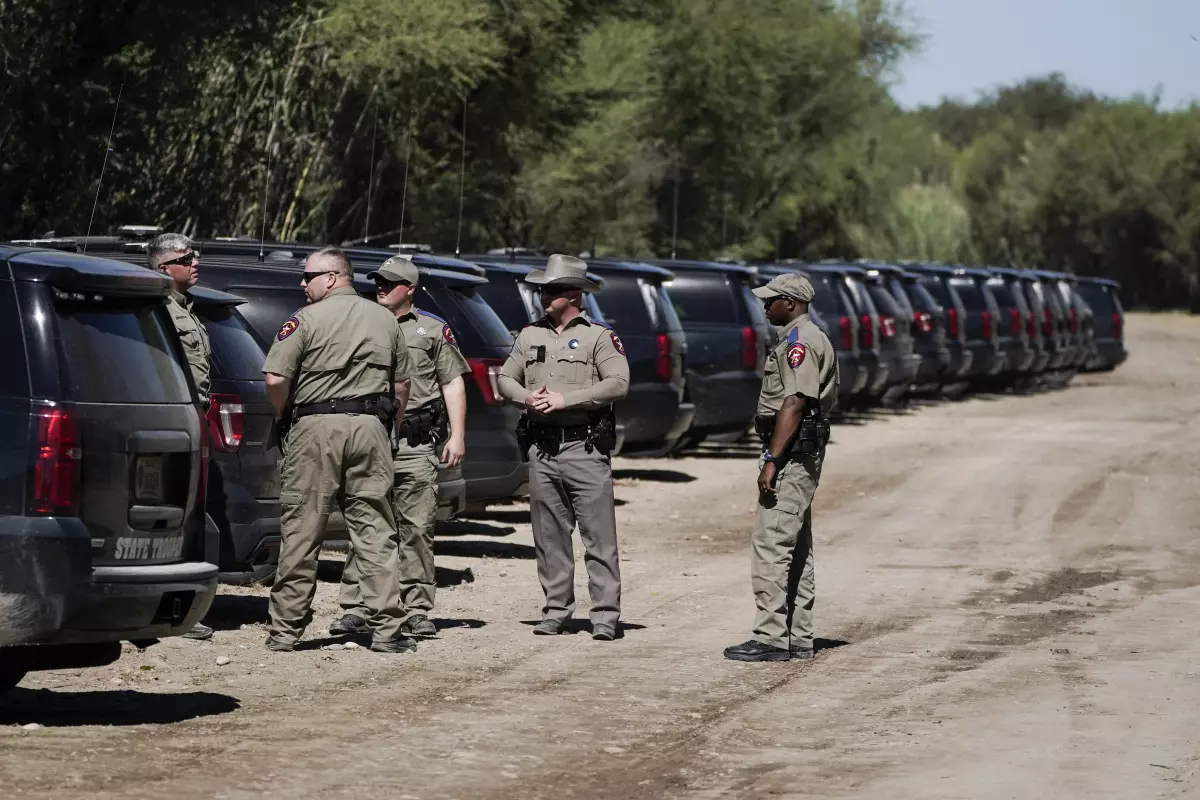 Texas Department of Public Safety officials stand near a lineup or vehicles parked near an encampment under the Del Rio International Bridge, Thursday, Sept. 23, 2021, in Del Rio, Texas.