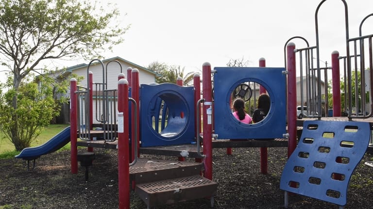 Two sisters play in a neighborhood playground that sits mostly...