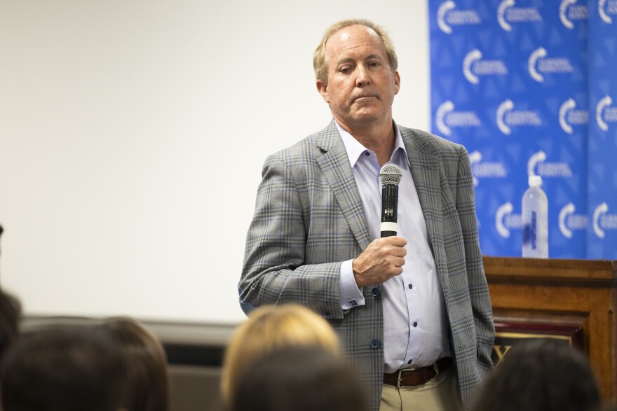 A man stands with a microphone speaking to an audience.