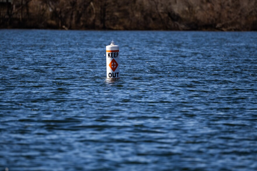 A “Keep Out” buoy floats in the water by I-35.
