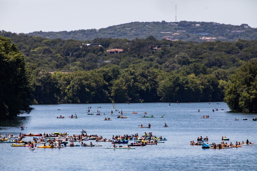 Crowds gather on stand up paddle boards, rafts and kayaks on Lady Bird Lake.