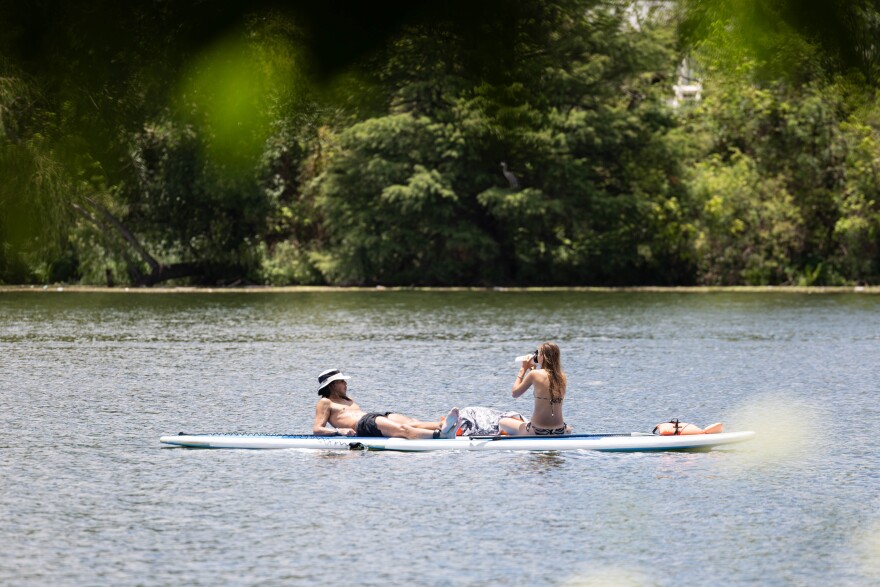 Paddle boarders drinking water on a 95-degree weather on Lady Bird Lake on June 25, 2024.